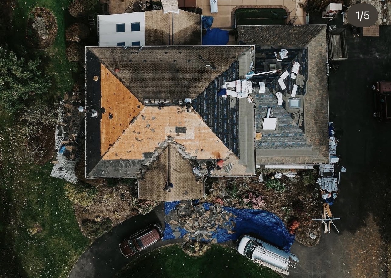 Aerial view of a residential roof mid-renovation with exposed plywood and roofing materials